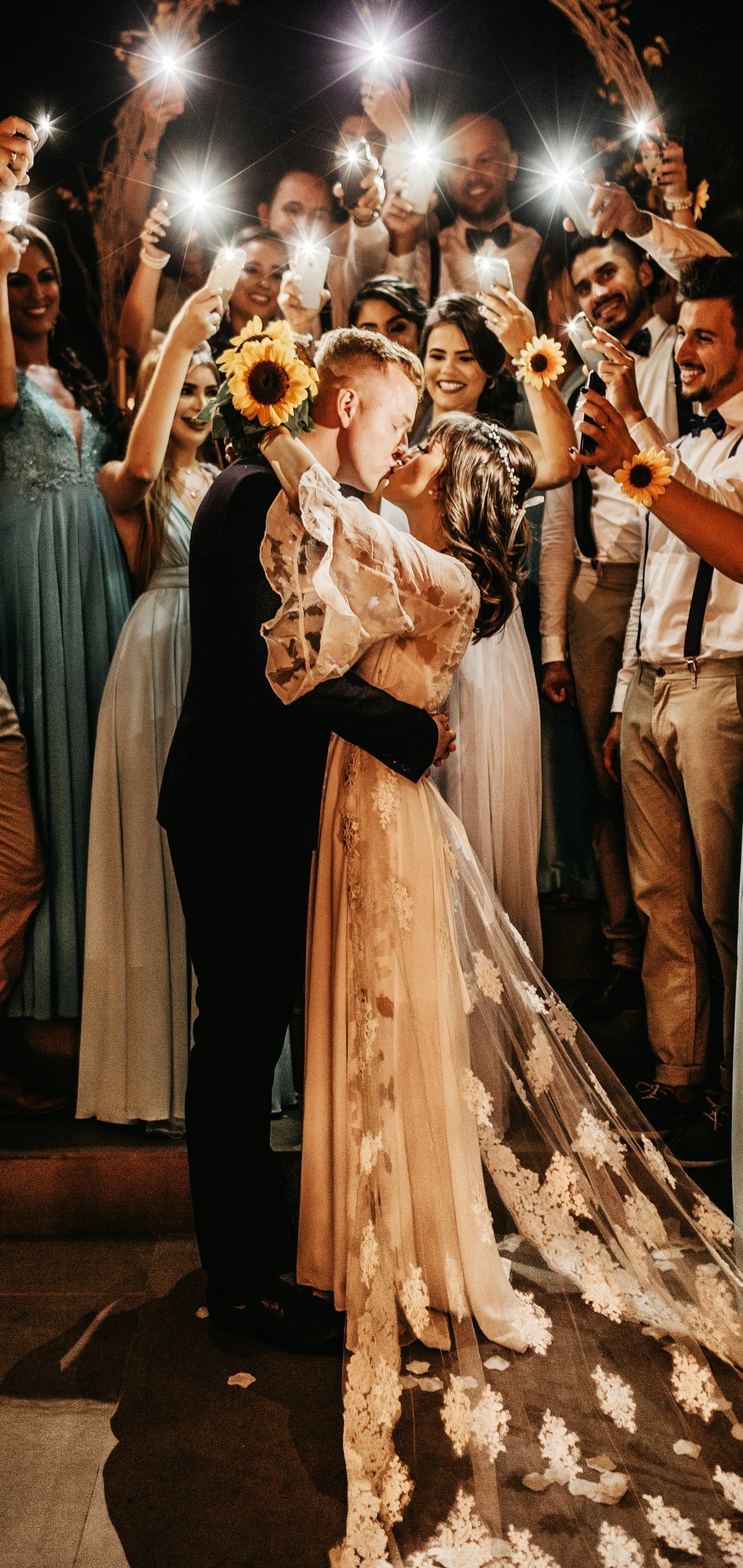 A couple kissing as their guests celebrate around them